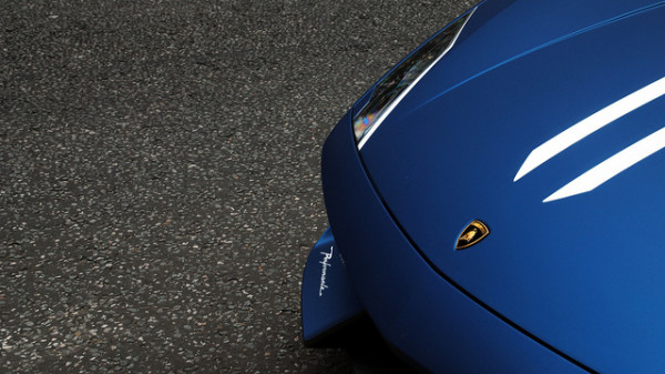 Close-up of a blue sports car's hood, showcasing sleek design and performance symbolism.