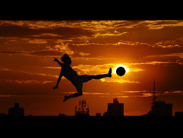 soccer player kicking ball at sunset