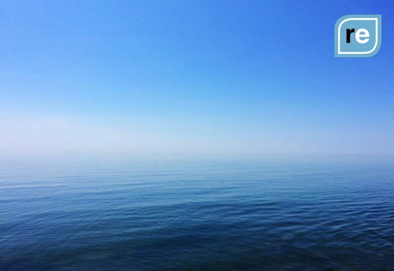 Serene seascape, hazy horizon, blue sky blend, calmness theme with 're' branding icon.