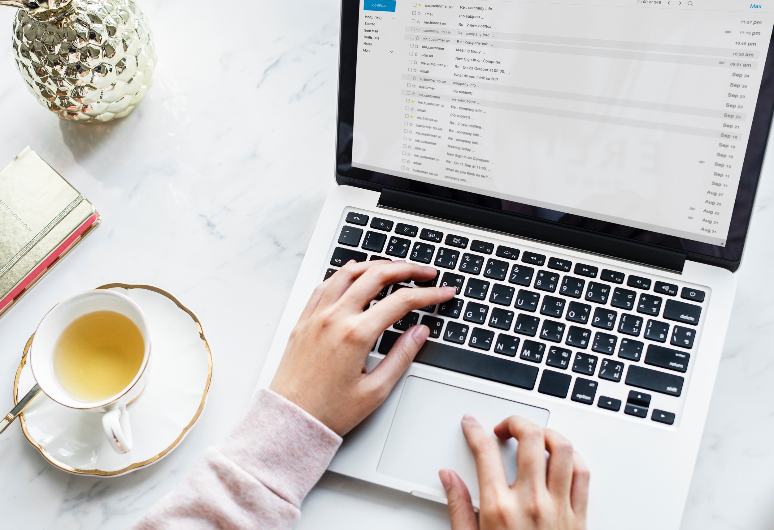 Hands typing on a laptop with an open email inbox, illustrating efficient email management with AI tools.